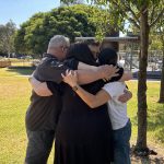 Four people hugging in a park.