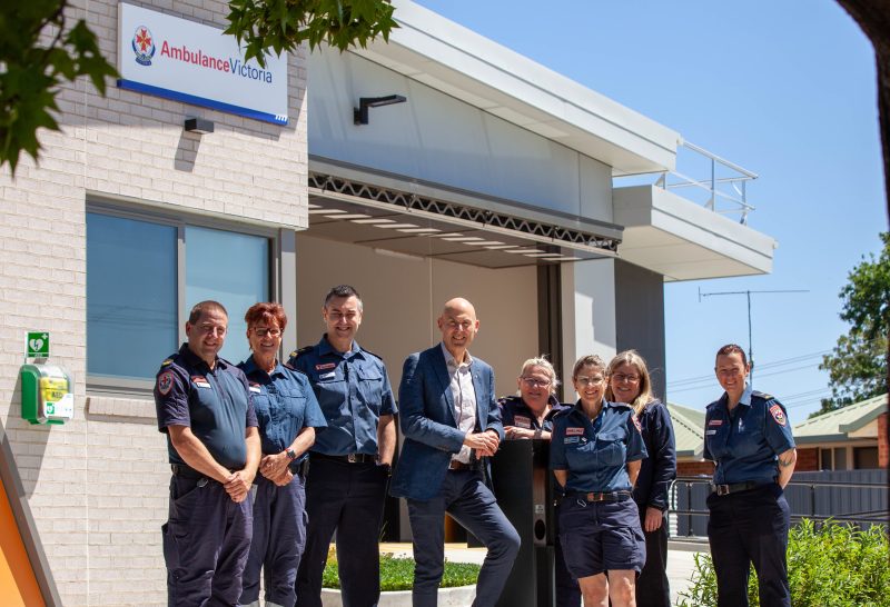 A group of smiling people in front of a building.