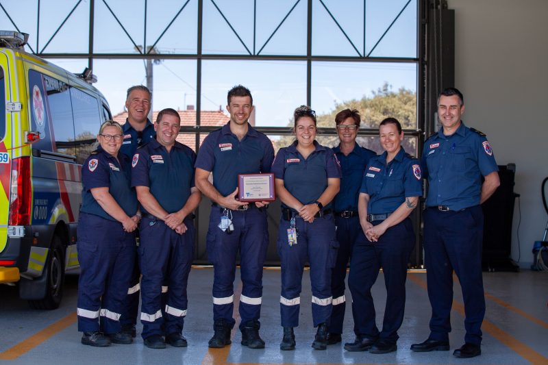 A group of paramedics holding a plaque.