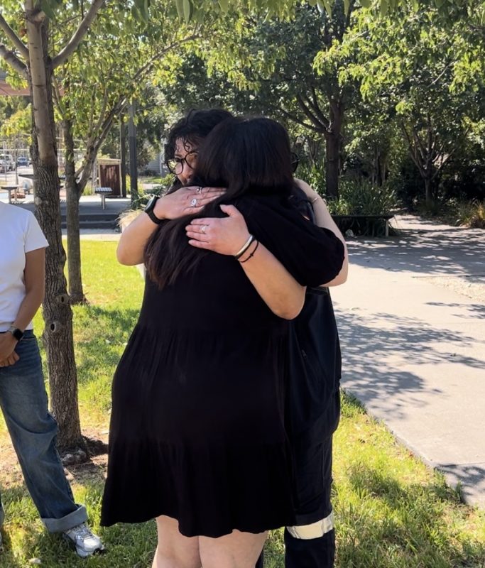 Two women hugging in a park.