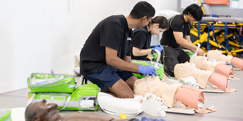 Several young people practicing breathing training on a manikin.