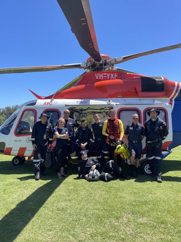 A group of paramedics and air crew standing beside an air ambulance helicopter