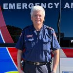 Kevin in uniform standing in front of an ambulance