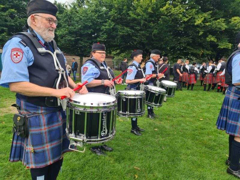 A line of drummers performing on the grass.