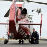 A man kneeling beside a helicopter.