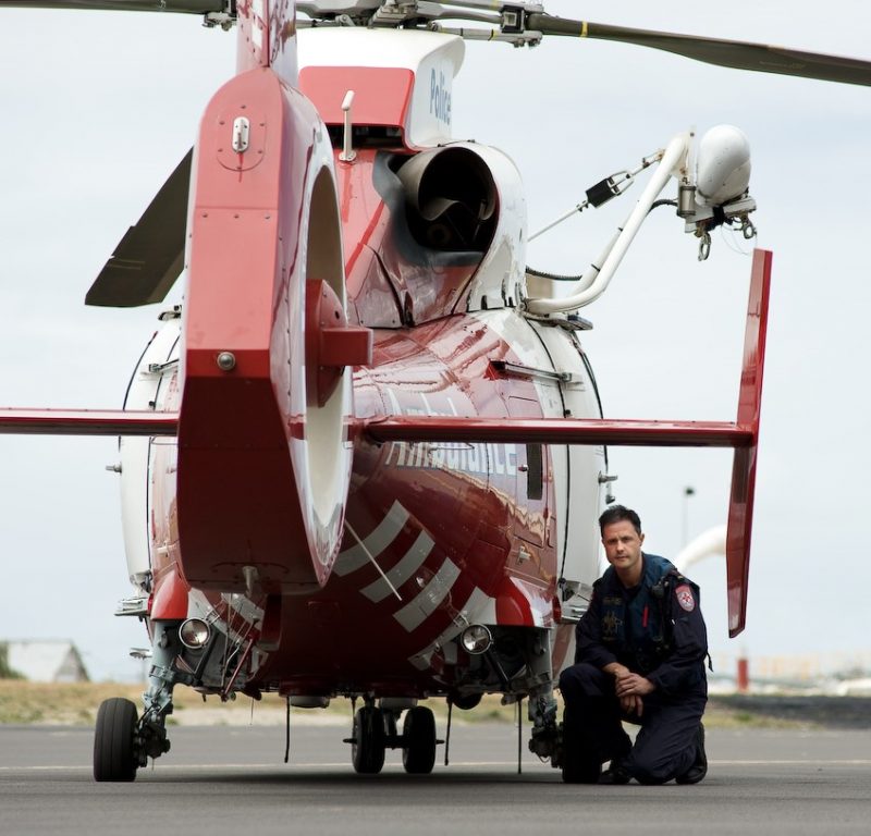 A man kneeling beside a helicopter.