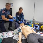 A male and female paramedic inserting a breathing tube into a mannequin.