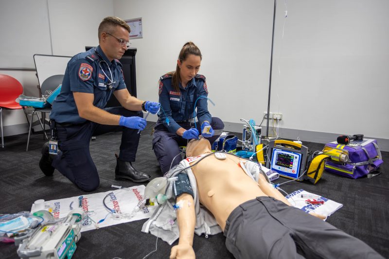 A male and female paramedic inserting a breathing tube into a mannequin.