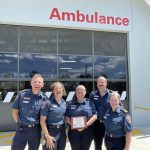 A group of smiling people holding a plaque.