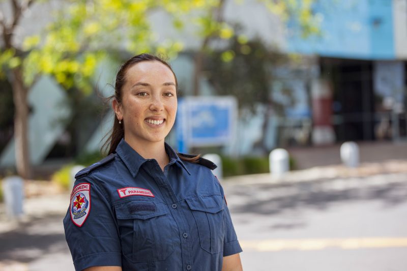 A brown-haired woman in paramedic uniform smiles for the camera.