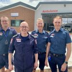 Four male paramedics standing in front of a building