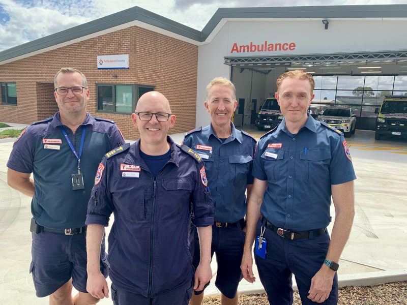 Four male paramedics standing in front of a building