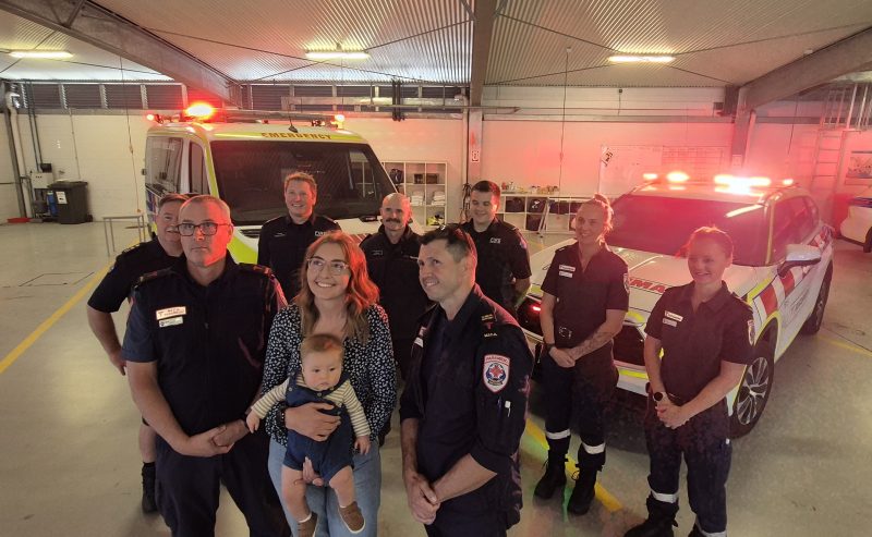 A group of people standing in front of ambulances.