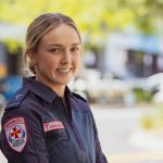 A blonde woman smiles for the camera in Ambulance Victoria paramedic uniform.