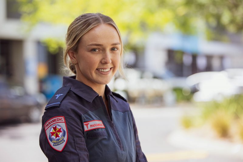 A blonde woman smiles for the camera in Ambulance Victoria paramedic uniform.