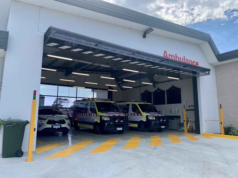 Three ambulance vehicles parked inside a large ambulance branch garage.